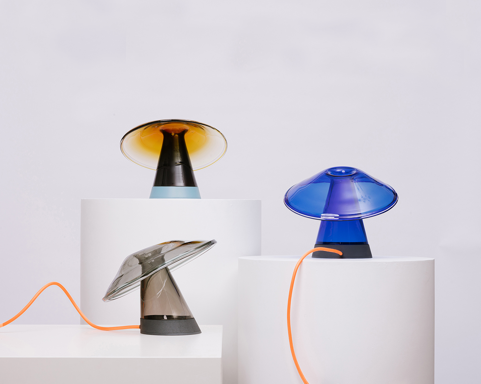 Cnidaria table lamp with smooth translucent glass form glowing softly against a dark studio background, evoking a calm, organic presence